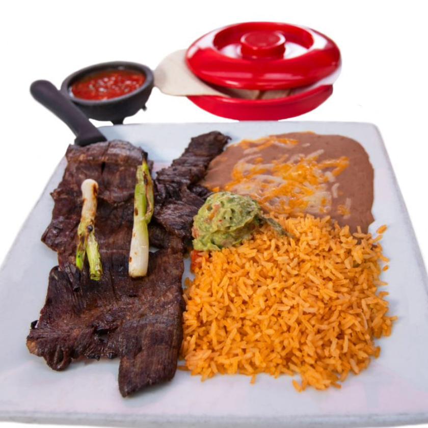 Carne Asada plate with grilled beef, Spanish rice, refried beans, guacamole, and salsa served with a tortilla warmer.