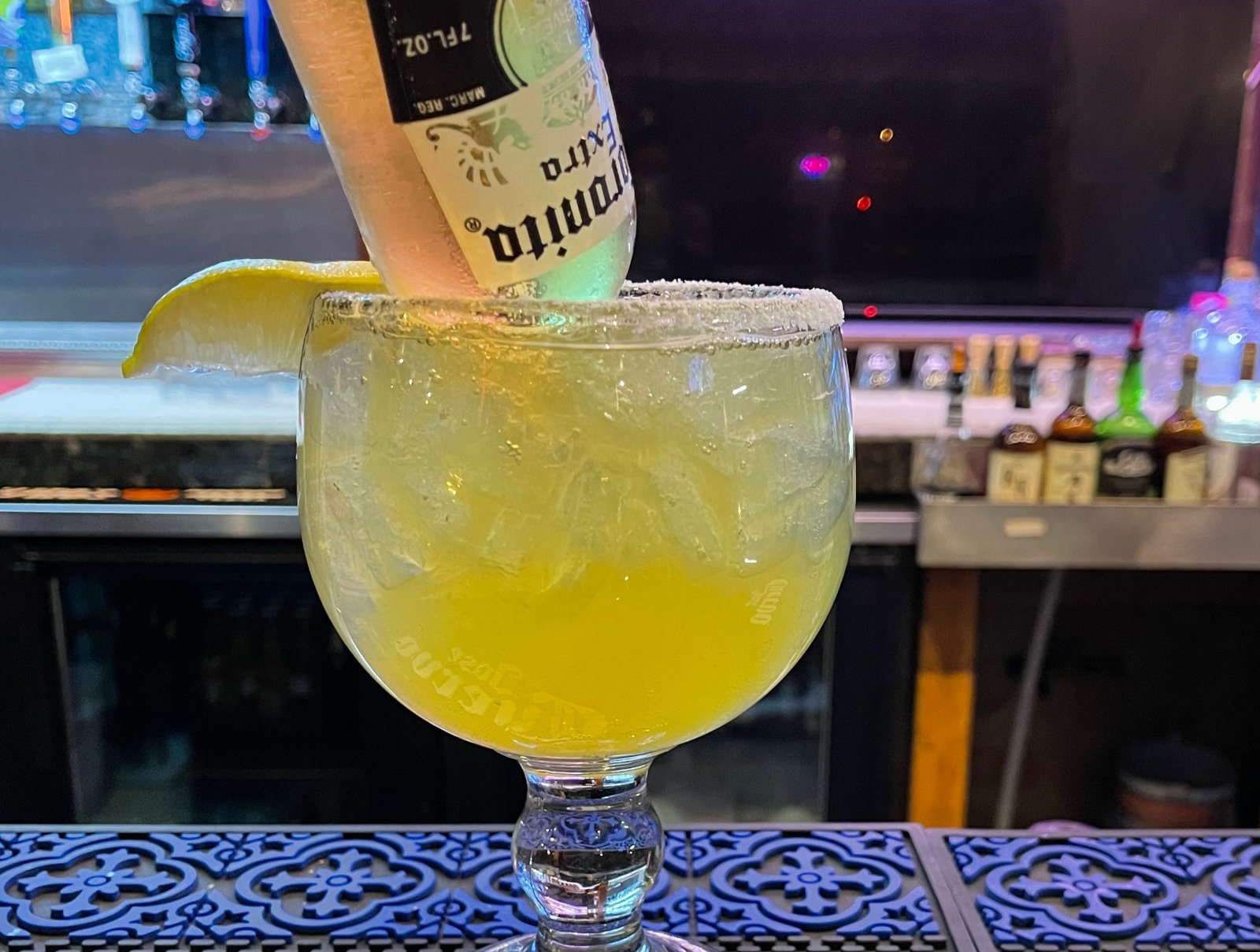 A Coronarita cocktail at Chihuahua Mexican Restaurant: a large margarita glass filled with a frozen lime drink, garnished with a lime wedge and an inverted Corona beer bottle.